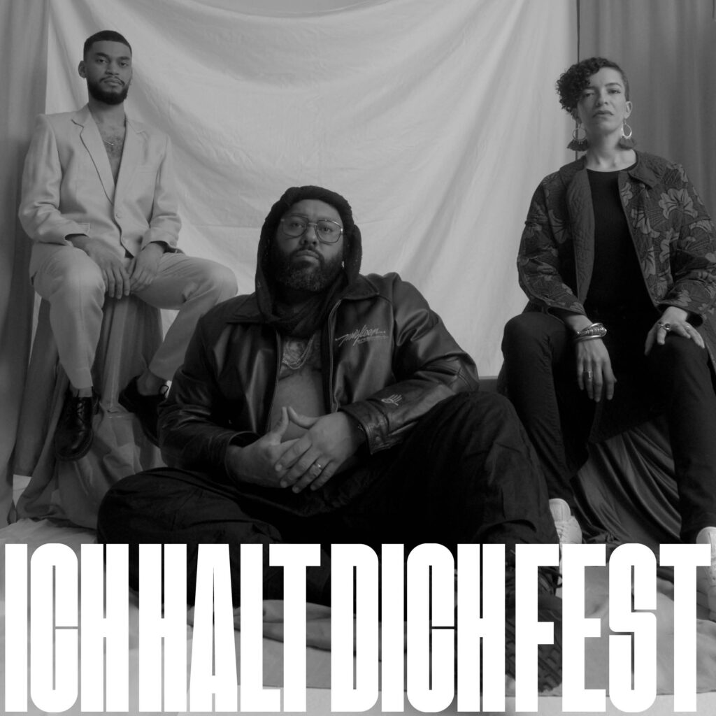 Cover der Single „Ich halt dich fest“. Schwarz-weiß-Fotografie von drei Personen vor einem drapierten Stoffhintergrund. In der Mitte sitzt Roger Rekless. Er trägt eine Brille, Kapuze und Lederjacke im Schneidersitz am Boden. Links sitzt FAYIM in einem hellen Anzug auf einem Hocker, rechts Celina Bostic, eine Person mit lockigem Haar, floral gemusterter Jacke und auffälligem Schmuck. Unten im Bild steht der Titel „ICH HALT DICH FEST“ in großen, weißen Blockbuchstaben.